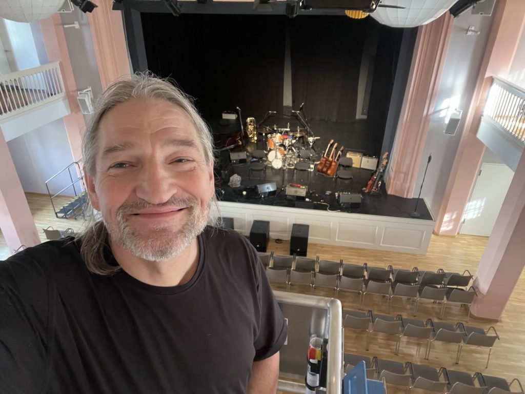 Selfie von Tontechniker Hubsi Widmann mit Bühne im Hintergrund