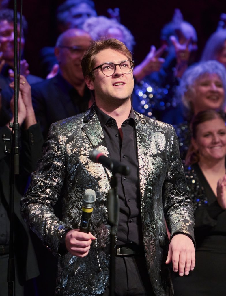 Nahaufnahme von Chorleiter Moritz Külbs im silbernen Jackett, März 2025